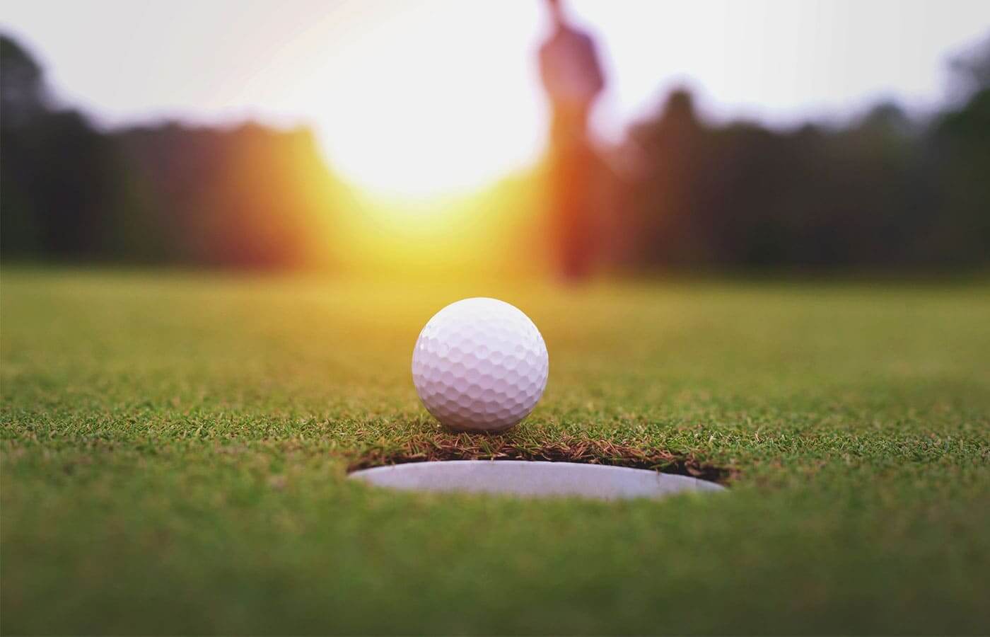 A golf ball sitting directly next to the hole